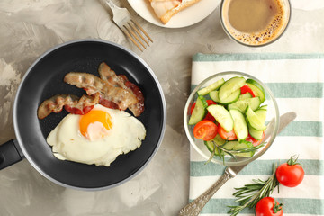 Frying pan with tasty egg and bacon for breakfast on table