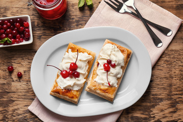 Tasty puff pastry dessert with berries and whipped cream on plate