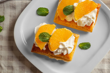 Tasty puff pastry dessert with orange and whipped cream on plate