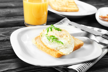 Plate with delicious over hard egg and bread slice on kitchen table