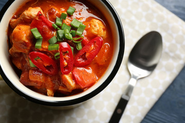 Enamel mug with delicious chili turkey on table, closeup