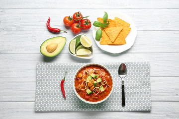 Delicious chili turkey, fresh vegetables and nachos on table