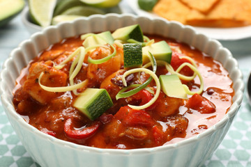Bowl with delicious chili turkey on table, closeup