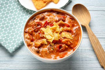 Bowl with delicious chili turkey and chips on wooden table