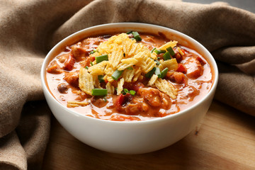 Bowl with delicious chili turkey and chips on table, closeup