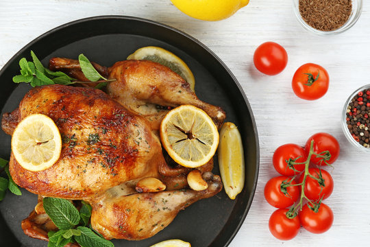 Homemade baked chicken with lemon and mint on table