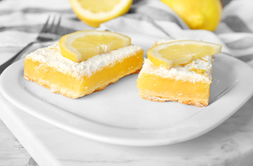 Plate with delicious lemon pie bars on table