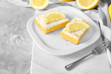Plate with delicious lemon pie bars on table