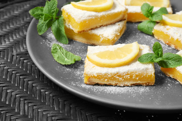 Plate with delicious lemon pie bars on table