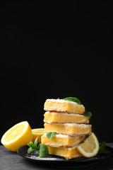 Plate with delicious lemon pie bars on black background