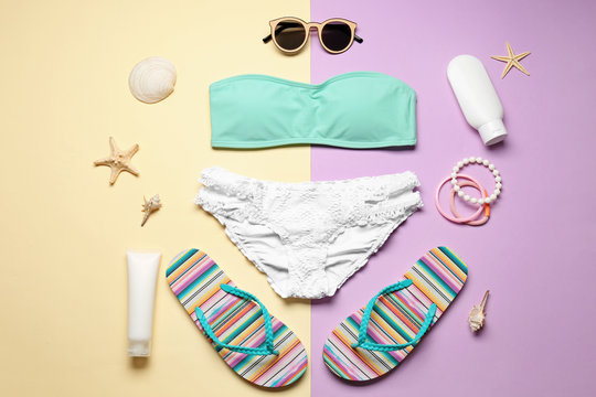 Beautiful bikini and beach accessories on color background