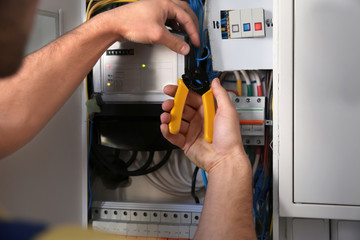 Electrician cutting wires in distribution board, closeup