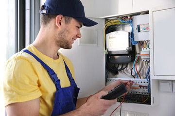 Electrician measuring voltage in distribution board