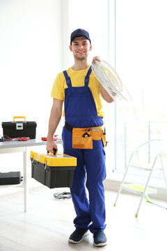 Young electrician with tools and wires at workplace