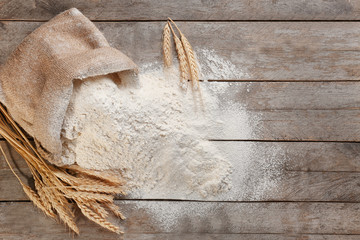 Bag with white flour on wooden background