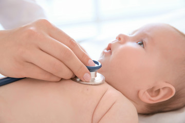 Doctor examining little baby with stethoscope in clinic, closeup. Baby health concept