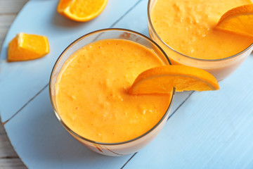 Delicious yogurt smoothie with orange on wooden background