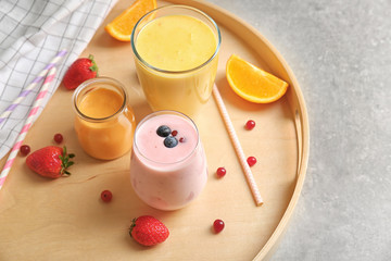 Fresh orange and blueberry yogurt smoothies on wooden tray