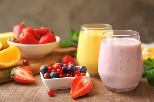 Fresh yogurt smoothies with orange and berries on wooden table
