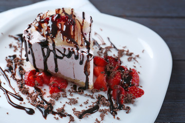 Plate with tasty cake and chocolate sauce on wooden table, closeup