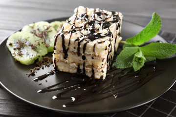 Plate with tasty cake and chocolate sauce on table, closeup