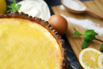Tasty lemon curd pie and ingredients on table, closeup
