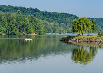 Fototapeta na wymiar Couple paddling in yellow canoe on tree lined lake