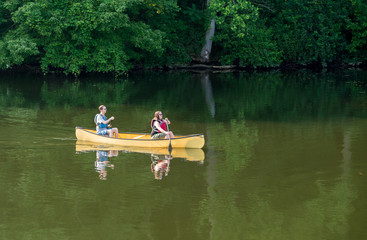 Couple paddling in yellow canoe on tree lined lake