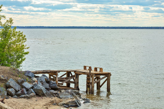 A small makeshift wooden pier and a bench of planks on the shore of the Ob reservoir