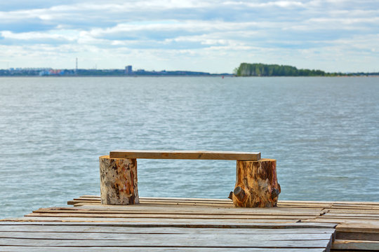 A small makeshift wooden pier and a bench of planks on the shore of the Ob reservoir