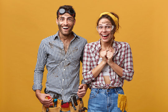 Attractive man and woman maintenance workers, technicians, electricians, plumbers or mechanics cheering, feeling happy and excited after got promoted. Postitive human facial expressions and emotions