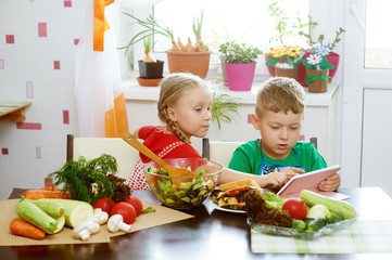 Children prepare salad vegetables . Happy kids in the kitchen . The concept of a healthy wholesome...