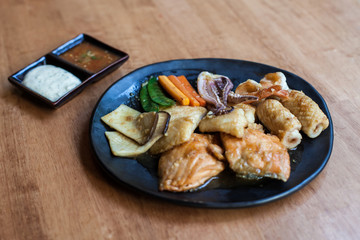 Seafood stire-fried with oil Japanese style cooking in the black disc on the wood table 