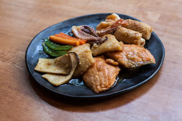Seafood stire-fried with oil Japanese style cooking in the black disc on the wood table 