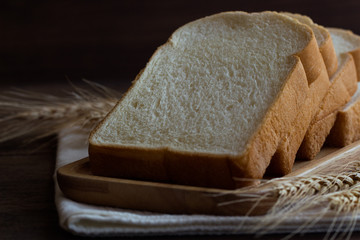 Sliced bread stack on wood plate. Homemade bread for breakfast put on rustic wood table. Soft and sticky homemade bread for delicious toast in breakfast. Homemade bakery background with copy space.