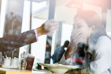 asian couple eating and laugh at restaurant view from outside window shop