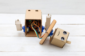  broken robot with hands on the white wooden background