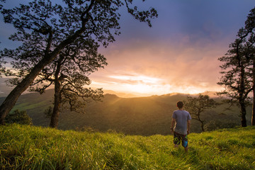 Naklejka na ściany i meble young man stand on mountain valley and enjoying sunset 