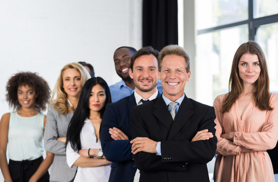 Boss With Group Of Businesspeople In Creative Office, Mature Successful Businessman Leading Business People Team Stand Folded Hands, Professional Staff Happy Smiling