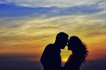 Young couple kissing in the flares of sunset light on a bridge construction in the city outdoors. copy space
