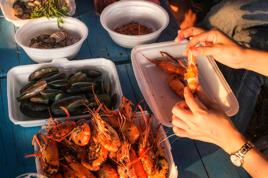 Woman eating grilled seafood mixed  sush as mussle, prawn and grilled prawn in her hand