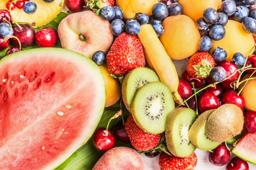 Variety of mix colorful summer fruits background: watermelon, sliced kiwi,banana, Peach, strawberry, pineapple, cherry, apricot, top view
