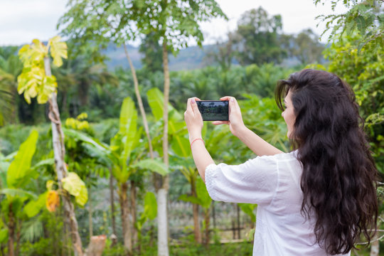 Woman Taking Photo Of Tropical Green Rain Forest Landscape On Cell Smart Phone Back Rear View