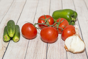 Сucumbers, tomatoes, peppers, onions on the wooden table.