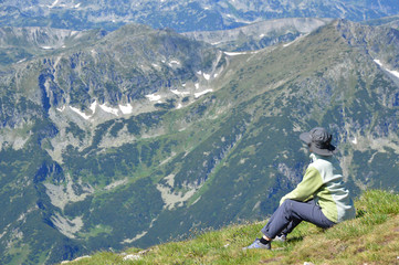 Naklejka premium Person hiker sitting on mountain peak