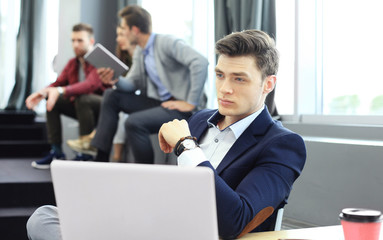 Young smart people are using gadgets while working hard in the modern office. Young man working on his laptop.