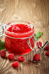 Ripe raspberry and raspberry jam on a wooden table.