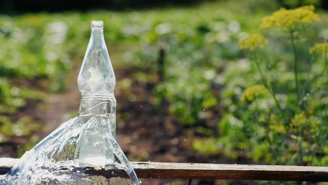 A bullet from an air rifle falls into a glass bottle of water. The bottle bursts, splashes fly. Slow motion video