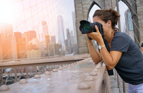 Woman taking pictures of Brooklyn bridge, NYC