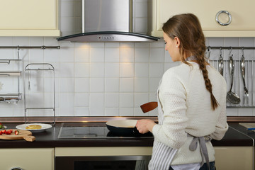 Woman standing back on kitchen indoor, preparing food, frying pancakes